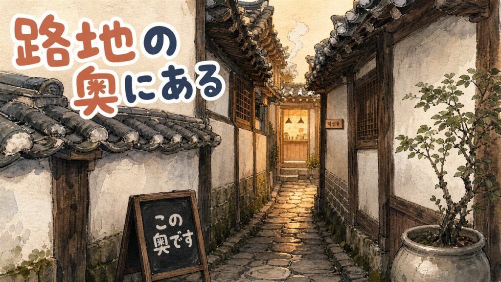 益善洞の瓦屋根が両側に迫る細い路地。奥のカフェの出入口から暖かい灯りがこぼれ、小さな看板が下がっている様子