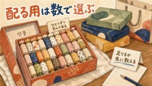 職場へのばらまき土産として、開けた箱の中に個包装のお菓子がぎっしり格子状に並び、奥に未開封の箱と紙袋が置かれている様子