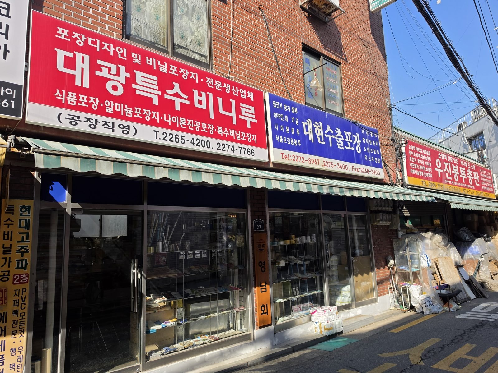 赤い看板の包装資材店が軒を連ねる方山市場の通り