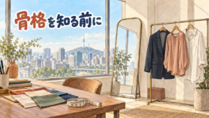 江南のスタイリングスタジオを描いた水彩イラスト。大きな窓の外にソウルの街と山の上の塔、室内には姿見と、形の違う3着（ジャケット・ブラウス・リネンシャツ）を掛けたハンガーラック、机の上に布の見本とメジャー。左上に「骨格を知る前に」の手書き文字