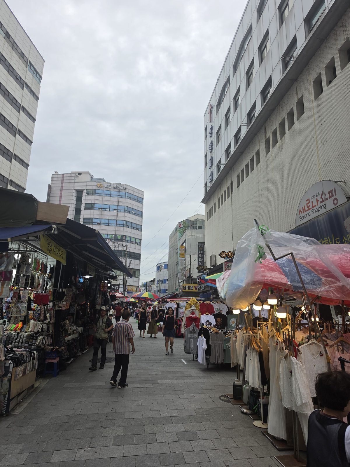 南大門市場の路地の右手に並ぶ露店と遠くの通行人