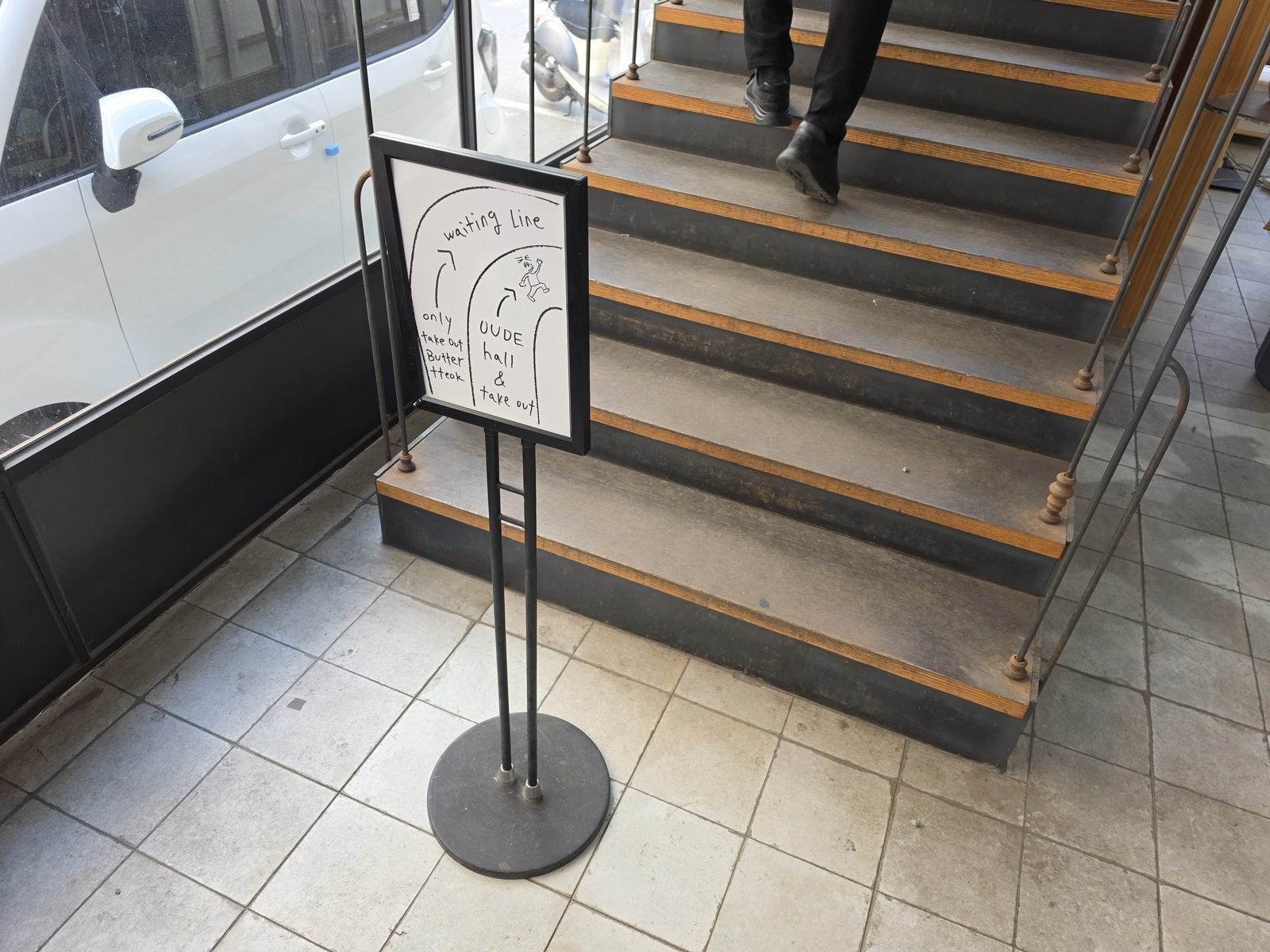階段脇に置かれたwaiting lineの手書き風案内スタンド