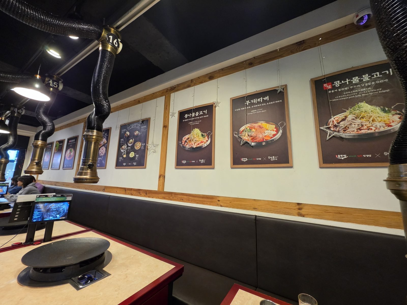 壁の写真つきメニューと席ごとの排気ダクトがある店内