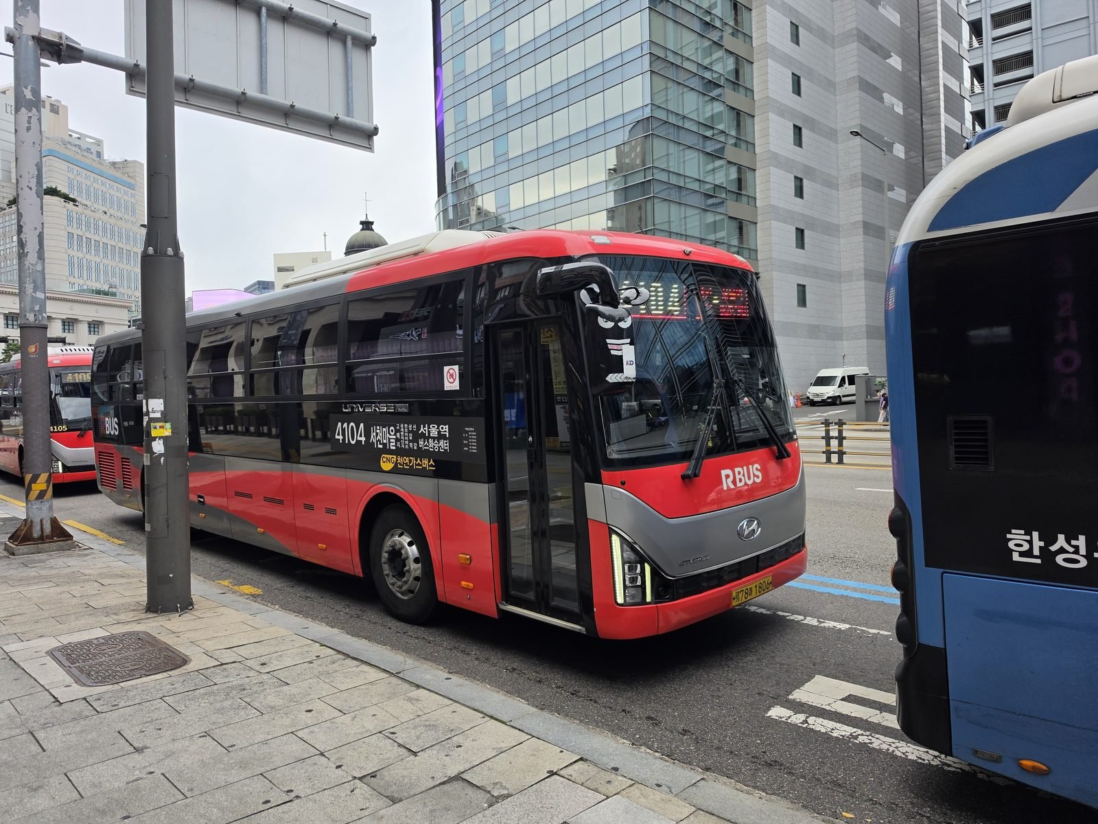 バス停に並んで止まる赤い広域バスと青バスの様子