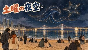 夜の広安里海水浴場の上空にドローンの光が広がり、広安大橋と砂浜から見上げる人々が並ぶ情景